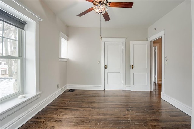 empty room featuring a ceiling fan, dark wood-style flooring, and baseboards