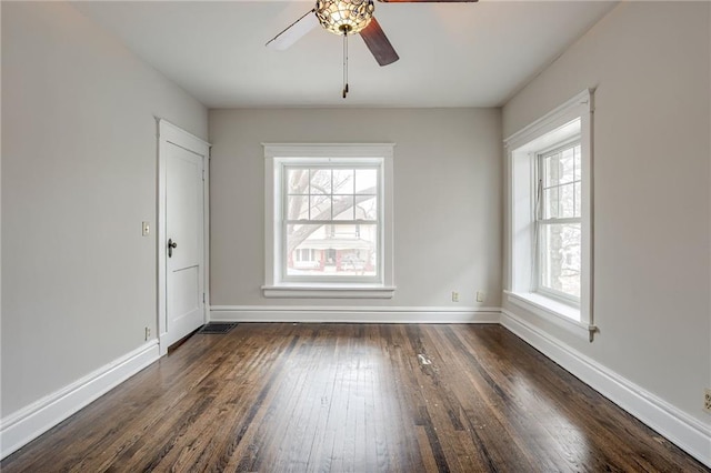 unfurnished room featuring dark wood finished floors, a ceiling fan, and baseboards