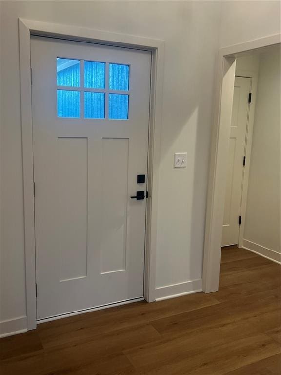 doorway featuring baseboards and wood finished floors