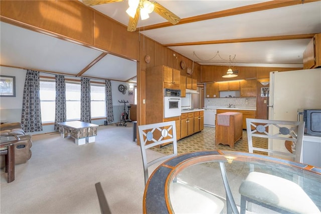 dining space featuring light carpet and vaulted ceiling with beams