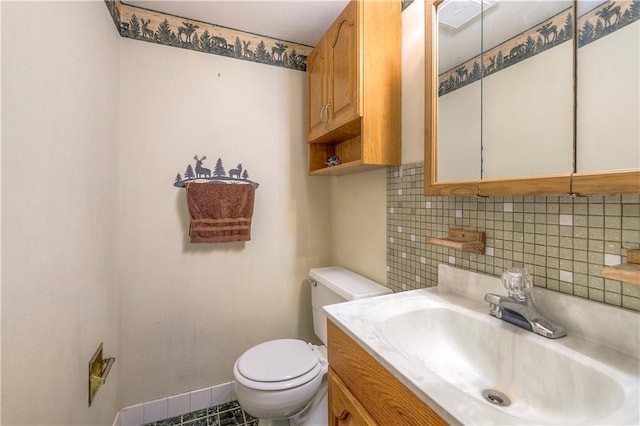 bathroom featuring baseboards, vanity, toilet, and decorative backsplash