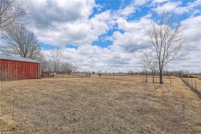 view of yard featuring a pole building, fence, an outdoor structure, and a rural view