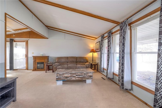 living area with lofted ceiling, light carpet, visible vents, and a glass covered fireplace