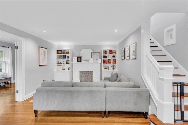 living area with stairs, light wood-type flooring, baseboards, and crown molding