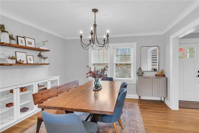 dining room with a chandelier, baseboards, crown molding, and light wood finished floors