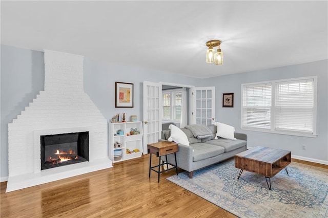 living room featuring a fireplace, baseboards, and wood finished floors