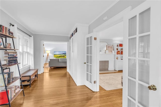 hall featuring light wood-type flooring, french doors, and crown molding