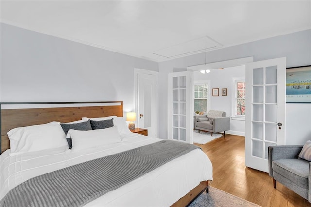 bedroom with french doors, wood finished floors, and attic access