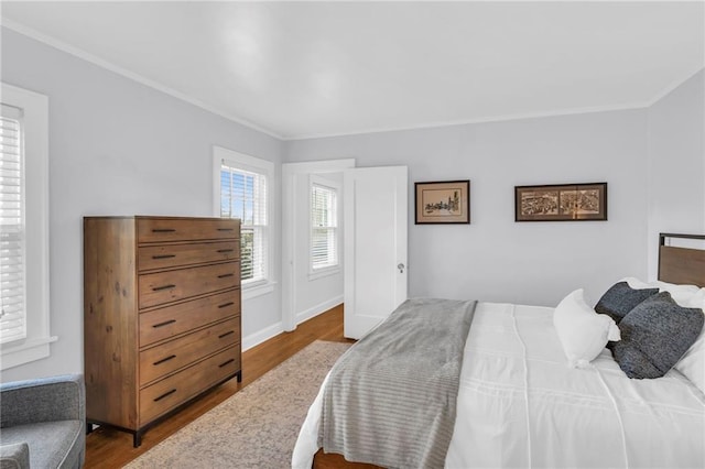 bedroom featuring baseboards, ornamental molding, and wood finished floors