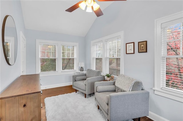 living area with vaulted ceiling, wood finished floors, a ceiling fan, and baseboards