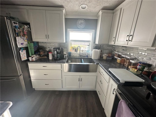 kitchen with dark wood finished floors, stainless steel appliances, decorative backsplash, a sink, and a textured ceiling