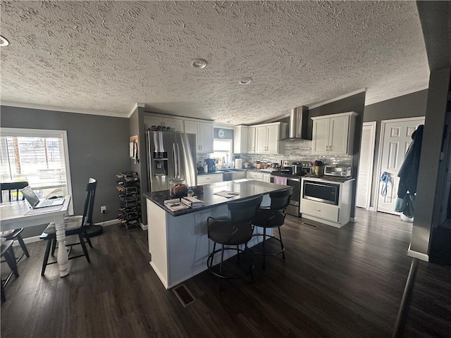 kitchen featuring wall chimney exhaust hood, dark wood finished floors, white cabinets, and stainless steel appliances