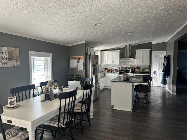 interior space with dark wood finished floors, stainless steel appliances, backsplash, a kitchen island, and wall chimney range hood