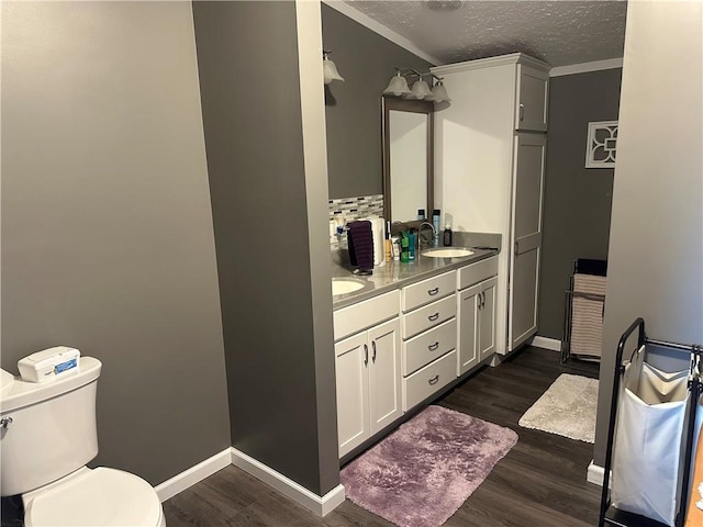 bathroom featuring double vanity, a textured ceiling, toilet, and wood finished floors