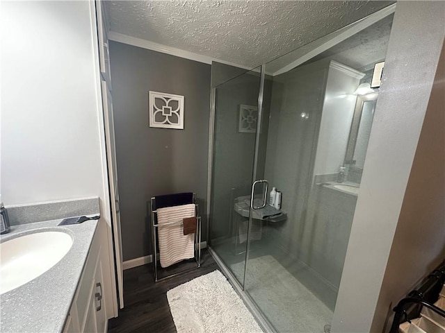 bathroom featuring baseboards, wood finished floors, a textured ceiling, vanity, and a shower stall