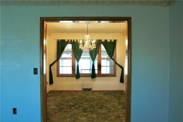 spare room featuring a chandelier, carpet flooring, visible vents, and baseboards