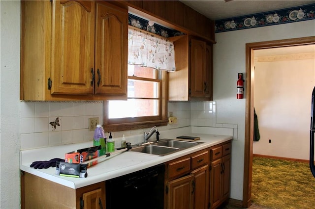 kitchen with a sink, black dishwasher, light countertops, backsplash, and brown cabinetry