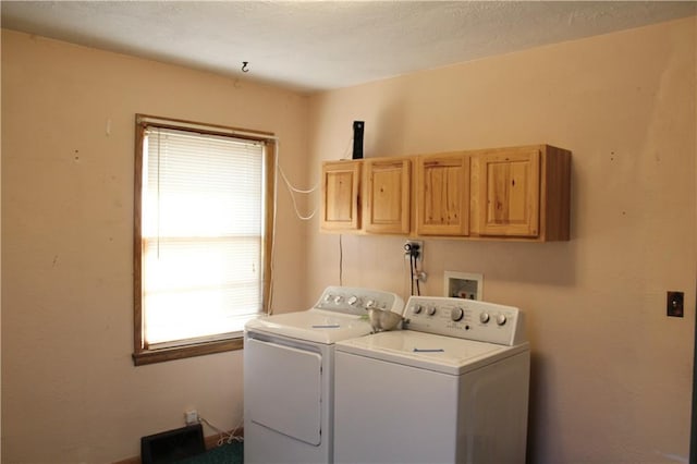 clothes washing area featuring washing machine and dryer and cabinet space