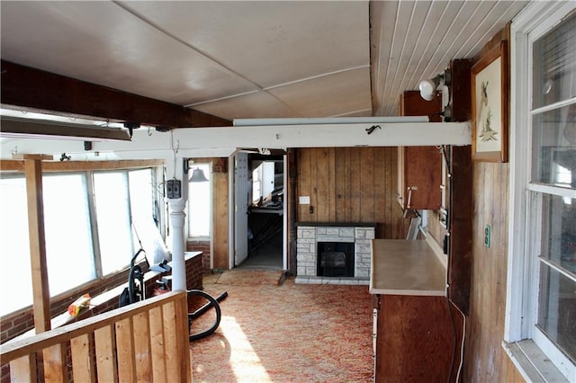 living room featuring wooden walls, carpet flooring, and a stone fireplace