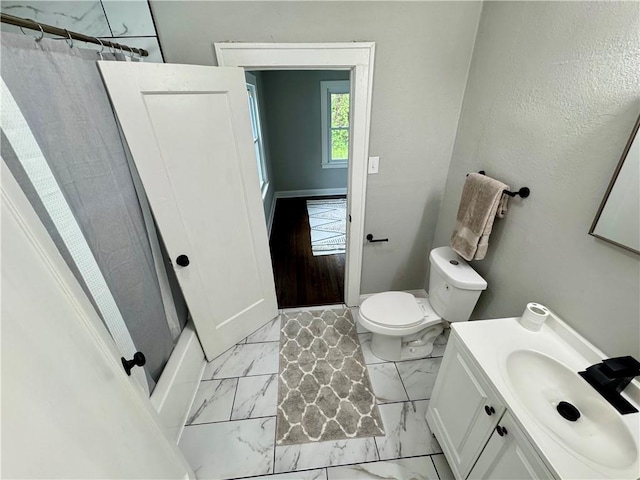 3003 E 52nd St, Kansas City, MO 64130 - bathroom featuring toilet, baseboards, marble finish floor, and vanity