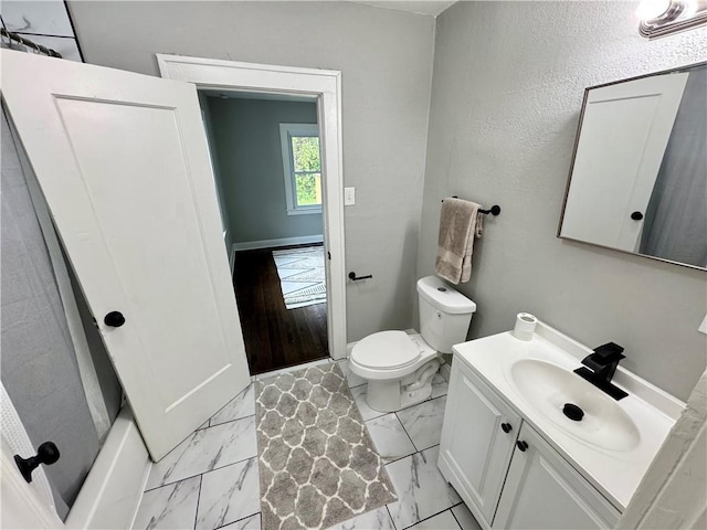 3003 E 52nd St, Kansas City, MO 64130 - bathroom with vanity, marble finish floor, baseboards, and toilet