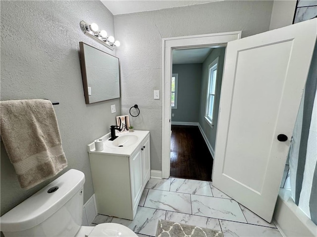 3003 E 52nd St, Kansas City, MO 64130 - full bathroom with vanity, baseboards, toilet, marble finish floor, and a textured wall