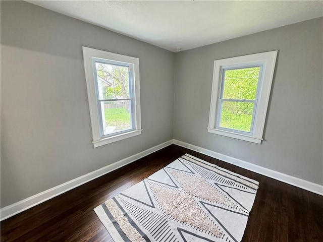 3003 E 52nd St, Kansas City, MO 64130 - spare room featuring baseboards, dark wood-style floors, and a healthy amount of sunlight