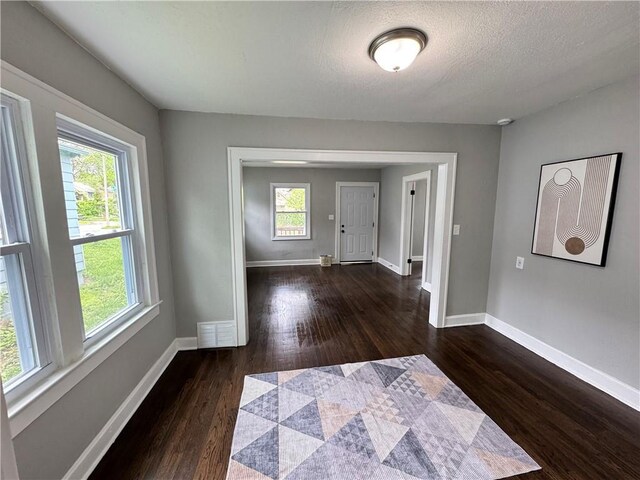 3003 E 52nd St, Kansas City, MO 64130 - interior space with baseboards, a textured ceiling, dark wood finished floors, and visible vents