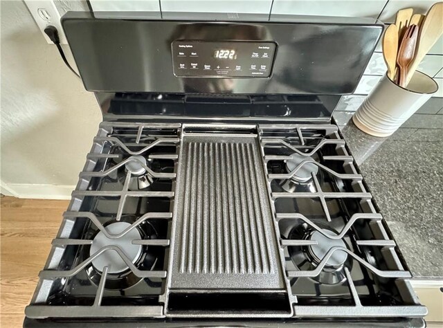 3003 E 52nd St, Kansas City, MO 64130 - details featuring baseboards, wood finished floors, and gas range