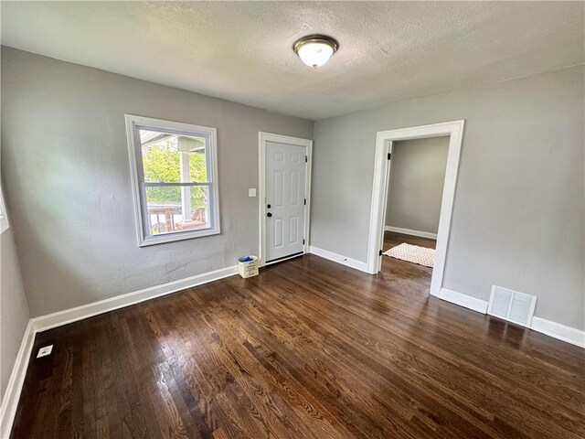 3003 E 52nd St, Kansas City, MO 64130 - unfurnished room featuring visible vents, a textured ceiling, dark wood finished floors, and baseboards