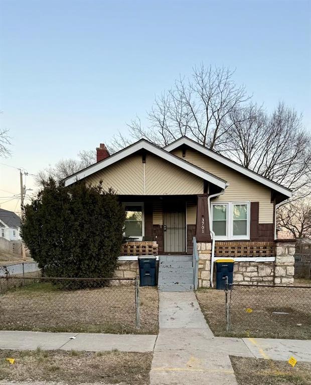 view of front of property with covered porch, a fenced front yard, and a chimney