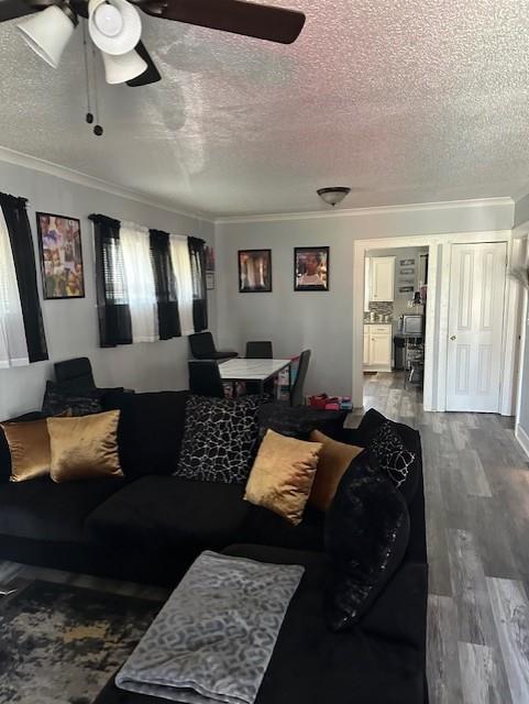 living area featuring a textured ceiling, crown molding, a ceiling fan, and wood finished floors