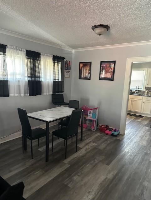 dining area featuring dark wood finished floors, a textured ceiling, and ornamental molding