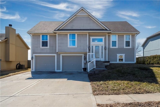 split foyer home featuring a garage, central AC, a shingled roof, and driveway