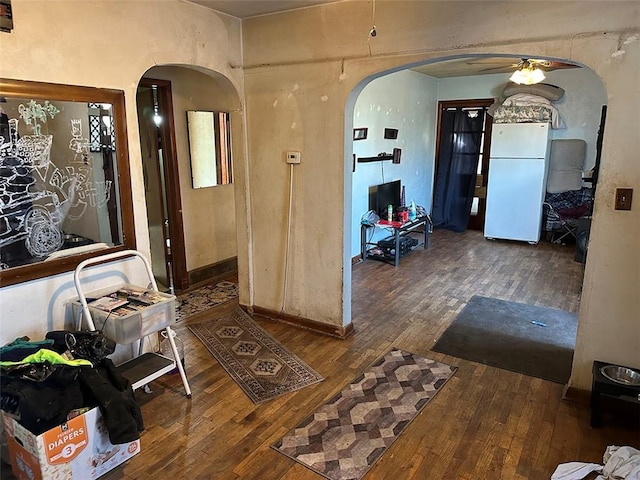 foyer featuring hardwood / wood-style flooring, baseboards, and arched walkways