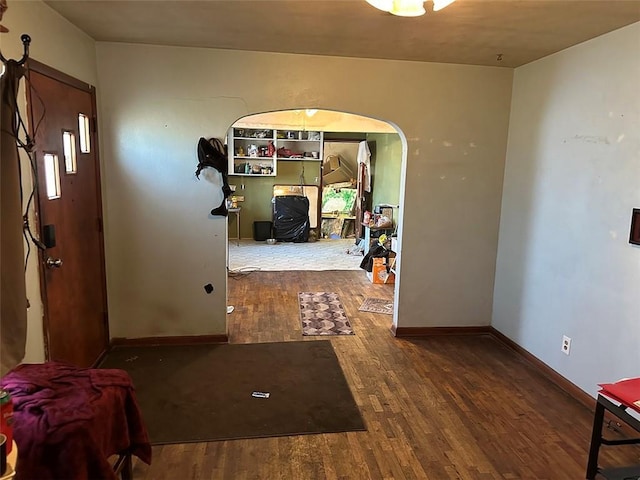 interior space with baseboards, arched walkways, and wood finished floors