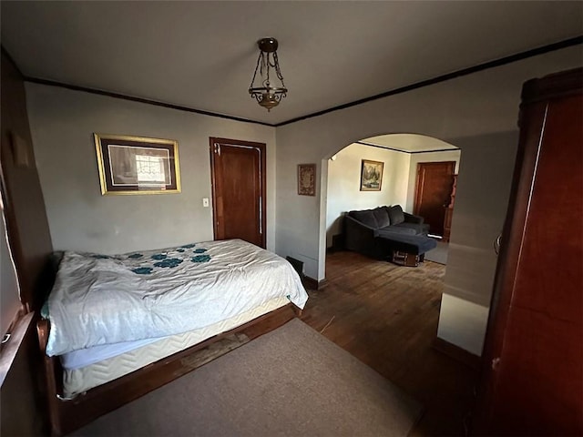 bedroom featuring arched walkways, dark wood-style floors, and crown molding