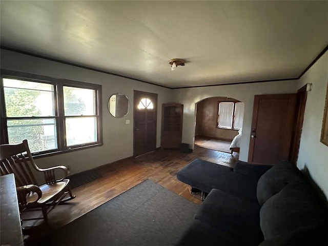 living room featuring arched walkways, wood finished floors, and crown molding