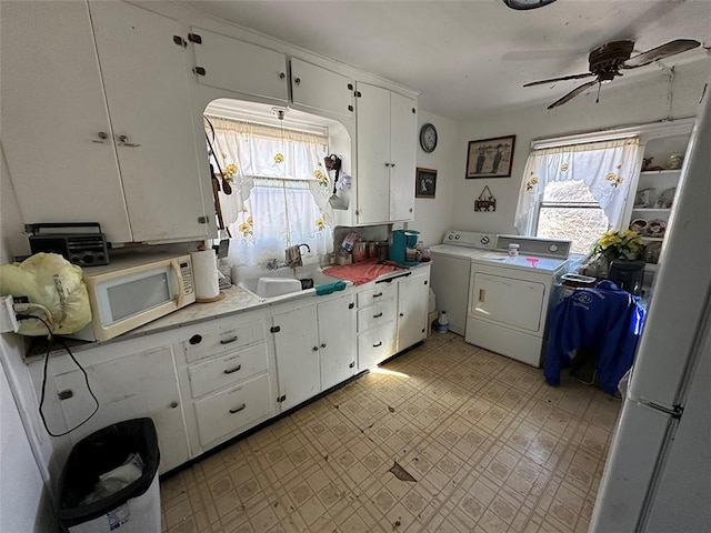 kitchen with light floors, light countertops, white microwave, white cabinets, and a sink