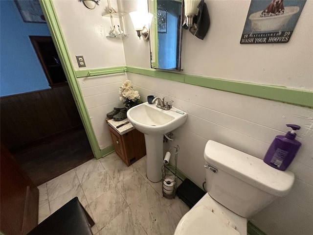 bathroom featuring marble finish floor, a wainscoted wall, and toilet