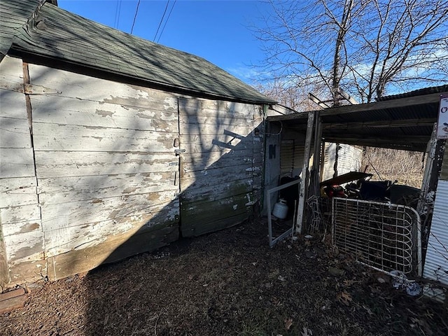 view of side of property with a shingled roof and an outbuilding