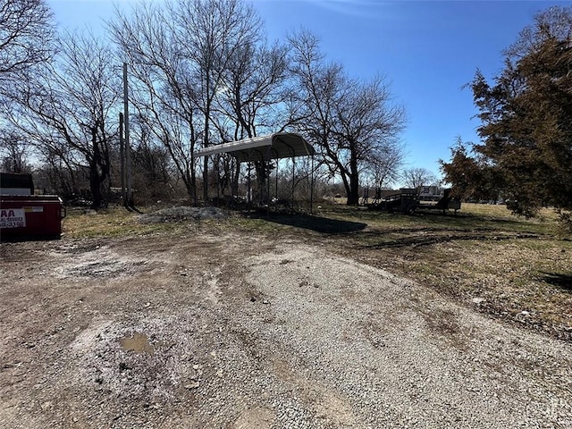 view of yard featuring a detached carport and dirt driveway