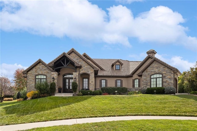 french country home with a front yard, french doors, a tiled roof, and stucco siding