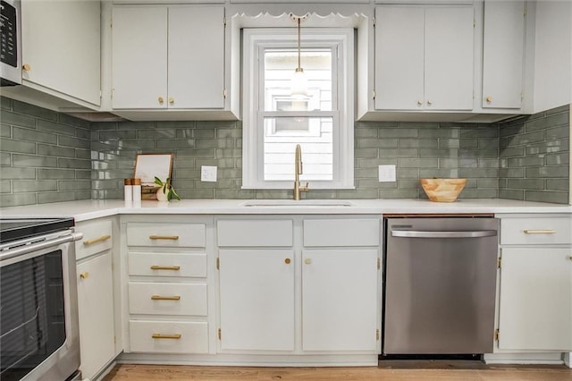 kitchen with stainless steel appliances, light countertops, a sink, and white cabinetry