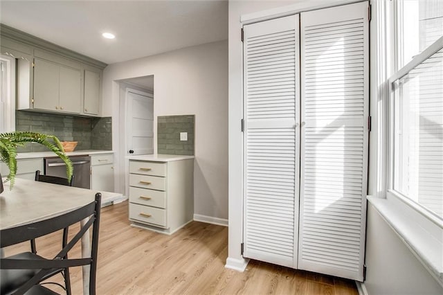 kitchen featuring light countertops, light wood finished floors, backsplash, and gray cabinets