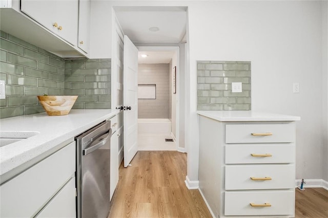 kitchen featuring light countertops, light wood-type flooring, white cabinets, and stainless steel dishwasher