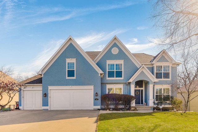 view of front facade with a front yard, driveway, an attached garage, and stucco siding