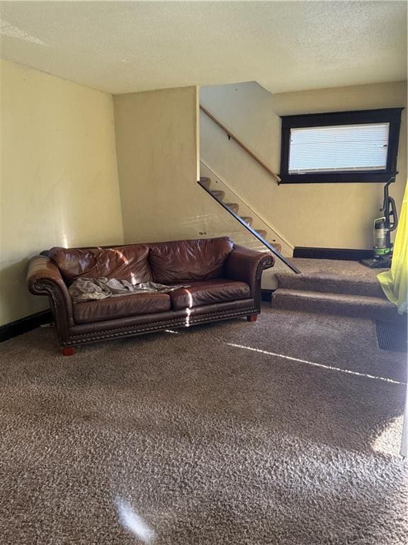 carpeted living room with stairway, baseboards, and a textured ceiling