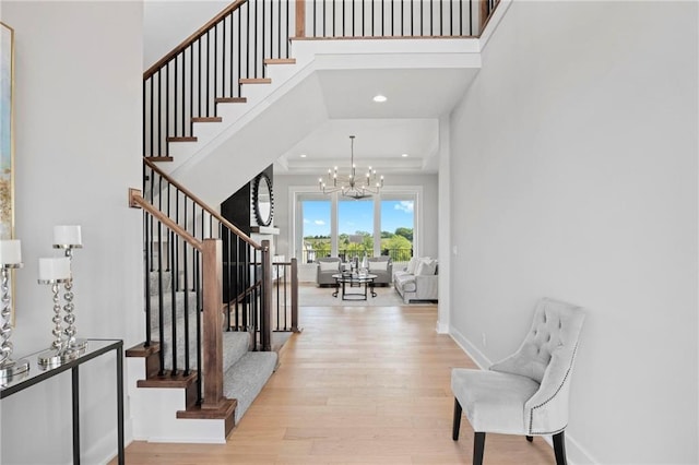 entryway with wood finished floors, a towering ceiling, baseboards, stairs, and an inviting chandelier