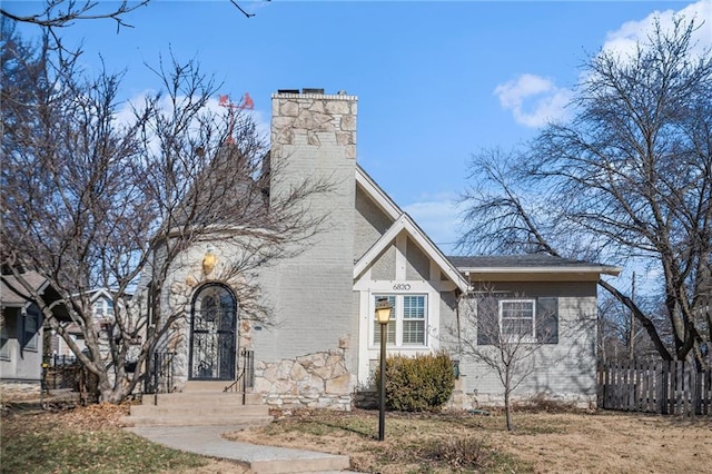 view of side of property with a chimney, fence, and brick siding